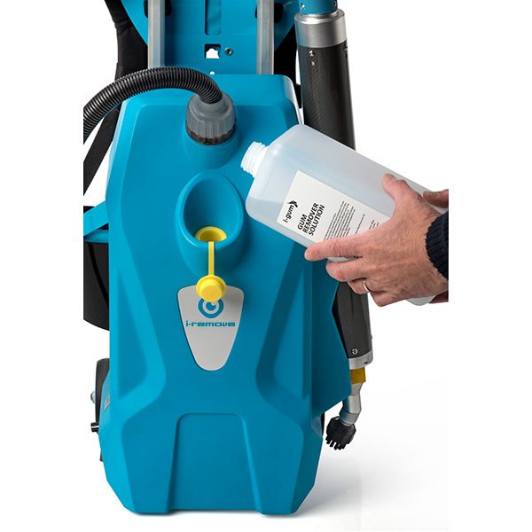 Eine Person gießt eine Flasche Flüssigkeit in eine blaue Maschine