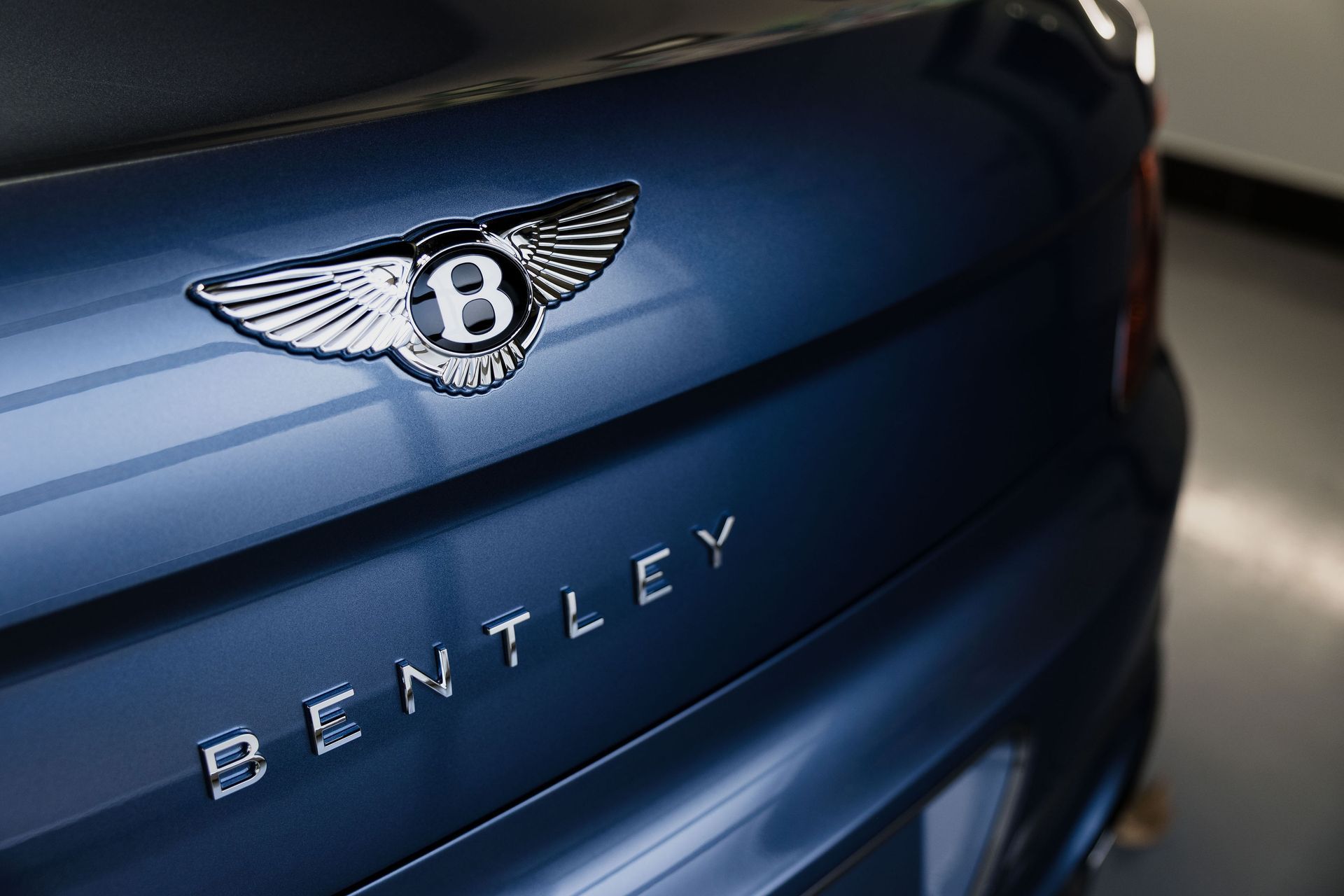 Close-up of a blue Bentley car trunk with the winged emblem and Bentley badge