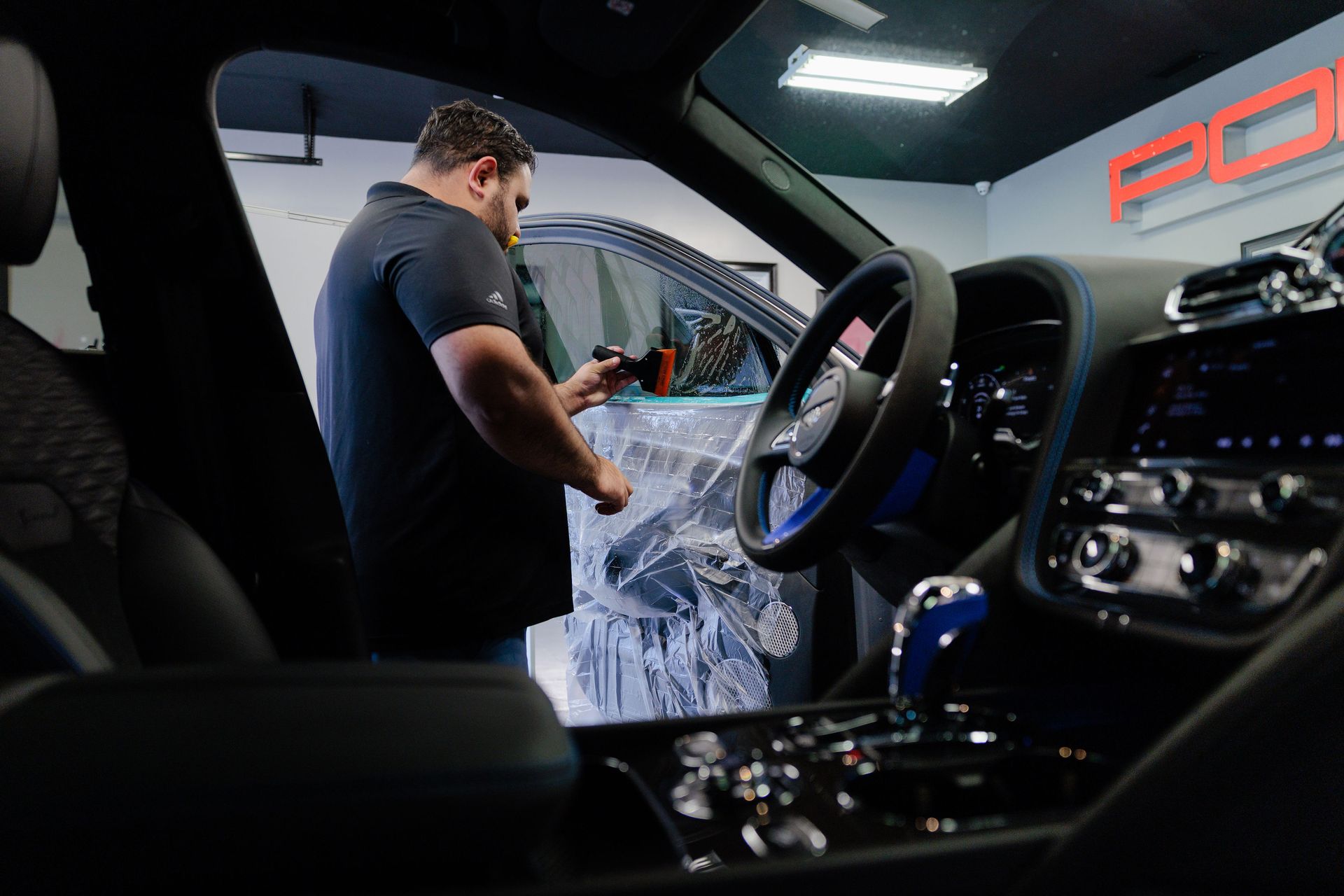 Man working inside a red interior Porsche. He is installing something on the door.