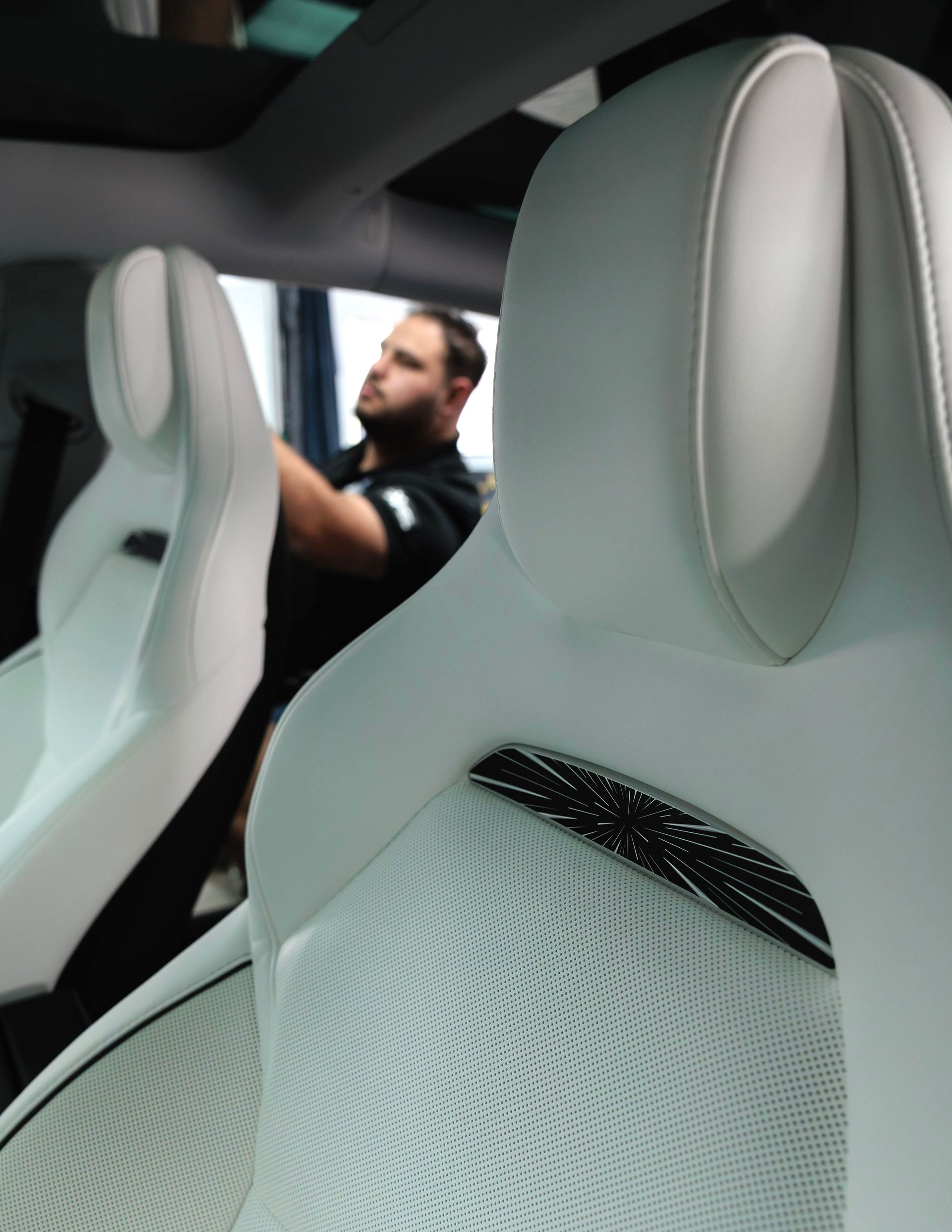 Modern car interior with white seats and a driver visible in the background