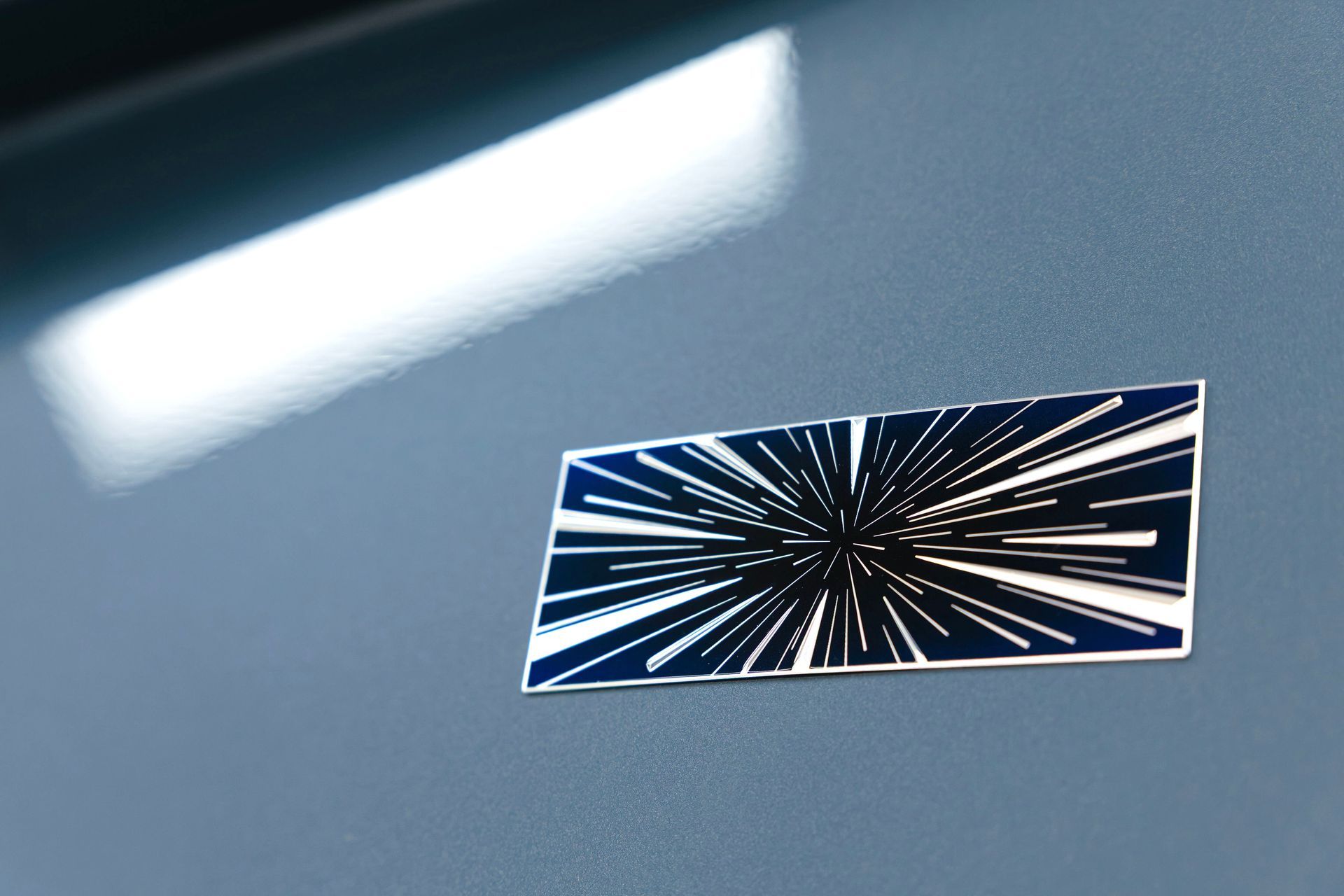 Blue wall with a small black-and-white starburst decal and a bright reflection above it