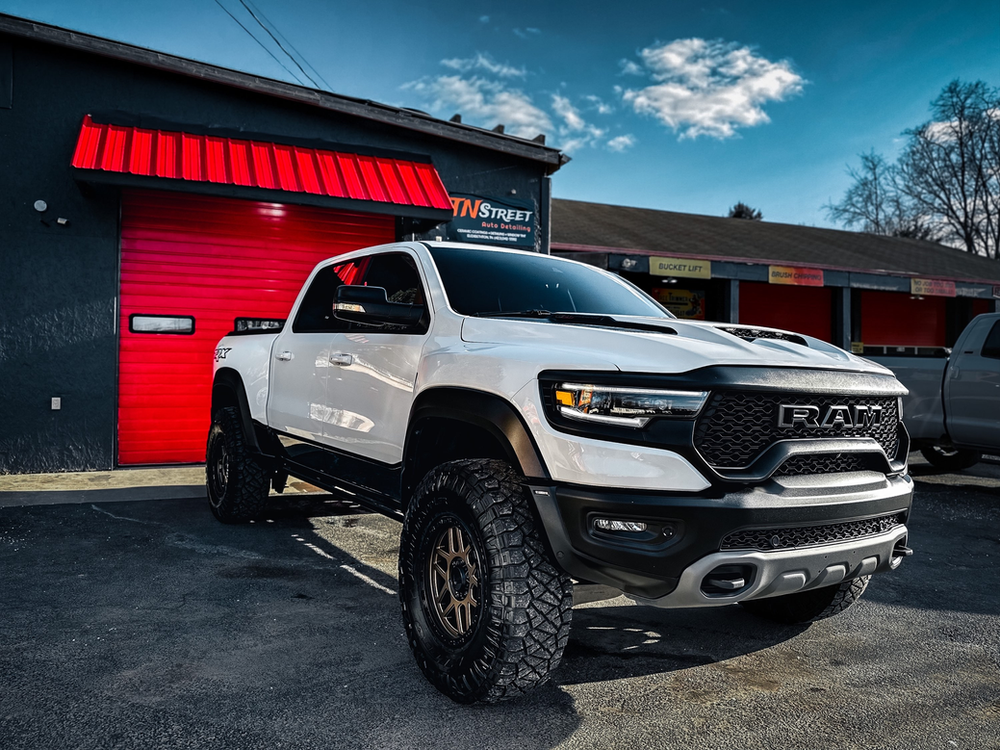 A white truck is parked in front of a red garage door.
