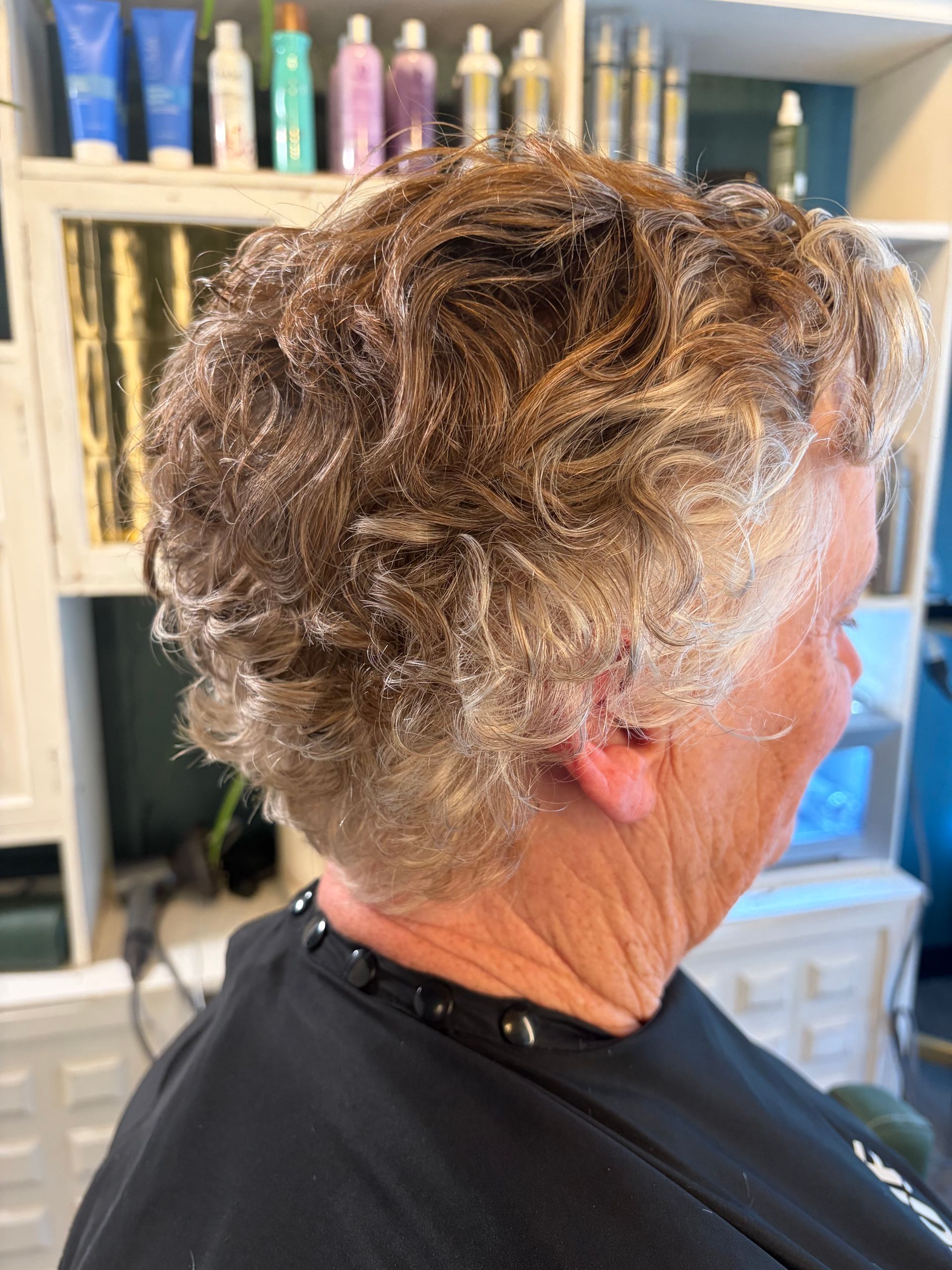A side view of a person wearing a salon cape with hair covered in light-colored styling product or treatment.