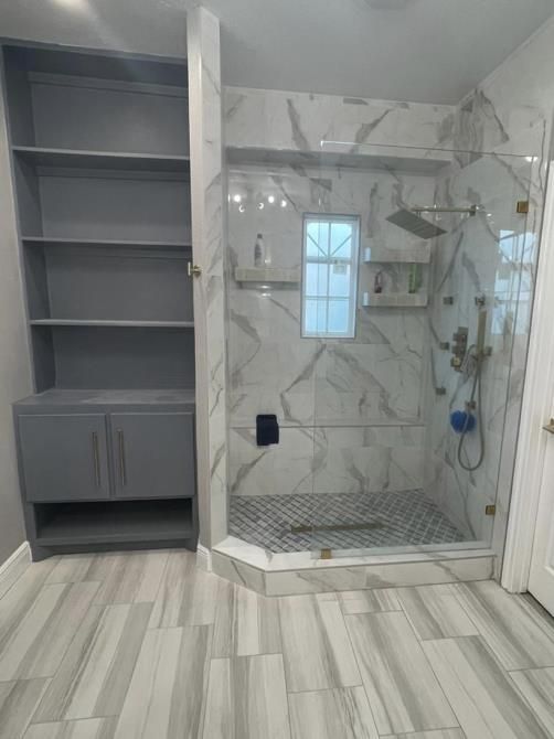 A bathroom with a walk in shower and a window.