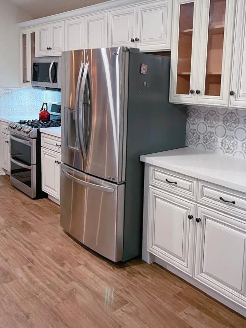 A kitchen with stainless steel appliances and white cabinets.