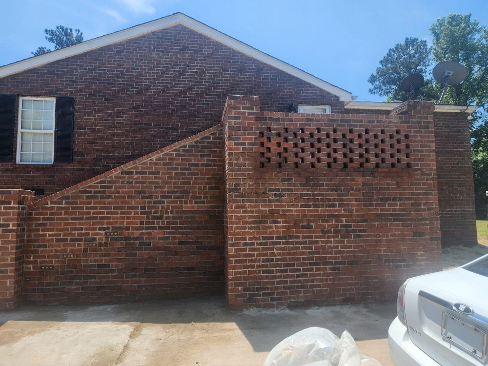 Brick house exterior with a brick privacy wall and parked white vehicle in the foreground