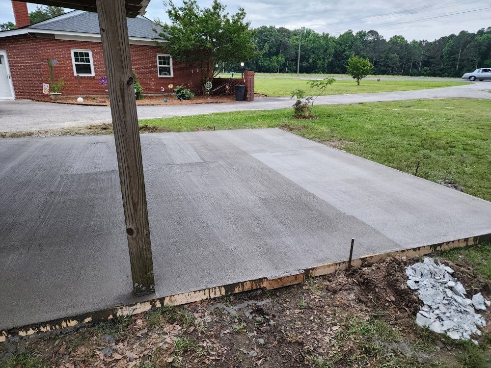 Concrete porch slab with a wooden post, facing a road and red brick house across a grassy yard