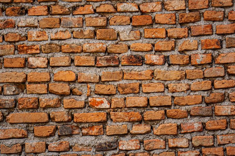 Orange brick wall with uneven mortar and weathered texture