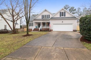 Suburban house with white siding, two-car garage, front porch, and a wide driveway