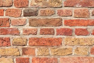 Close-up of a weathered red and tan brick wall with gray mortar lines