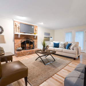 Bright living room with brick fireplace, beige sofa, woven rug, and coffee table in a cozy, modern setting