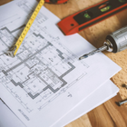 Blueprint on wooden desk with measuring tape, drill, and level for home renovation