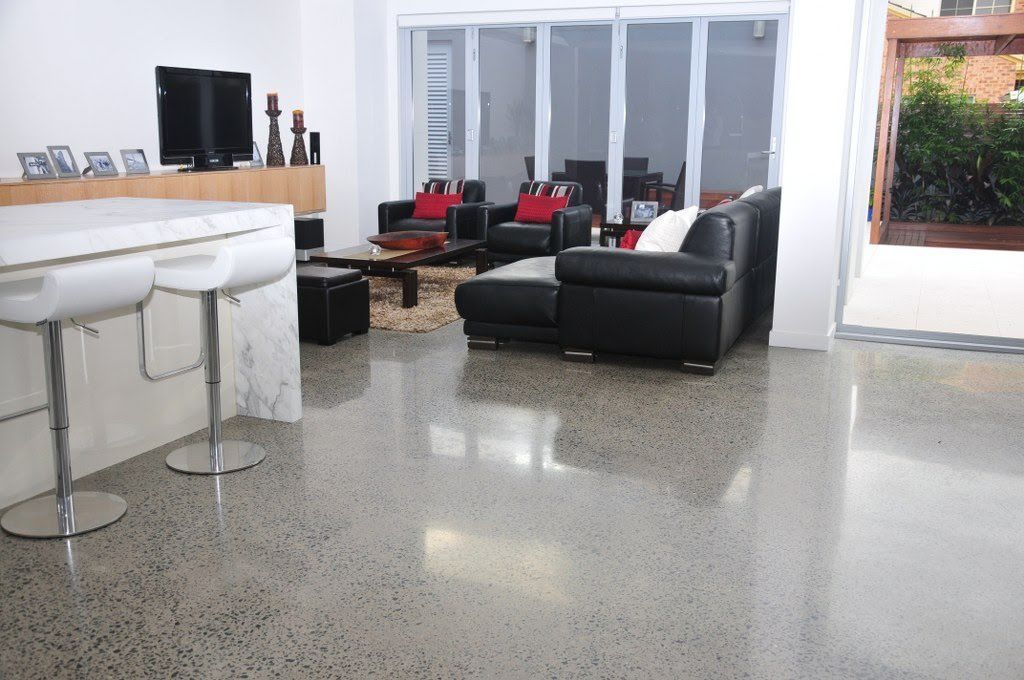 Modern lobby with white bar stools, black sofas, red chairs, and a polished floor