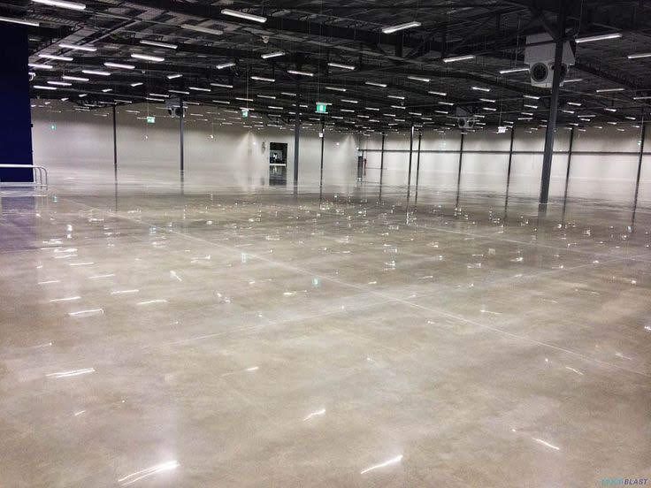 Empty warehouse with polished concrete floor and overhead industrial lighting