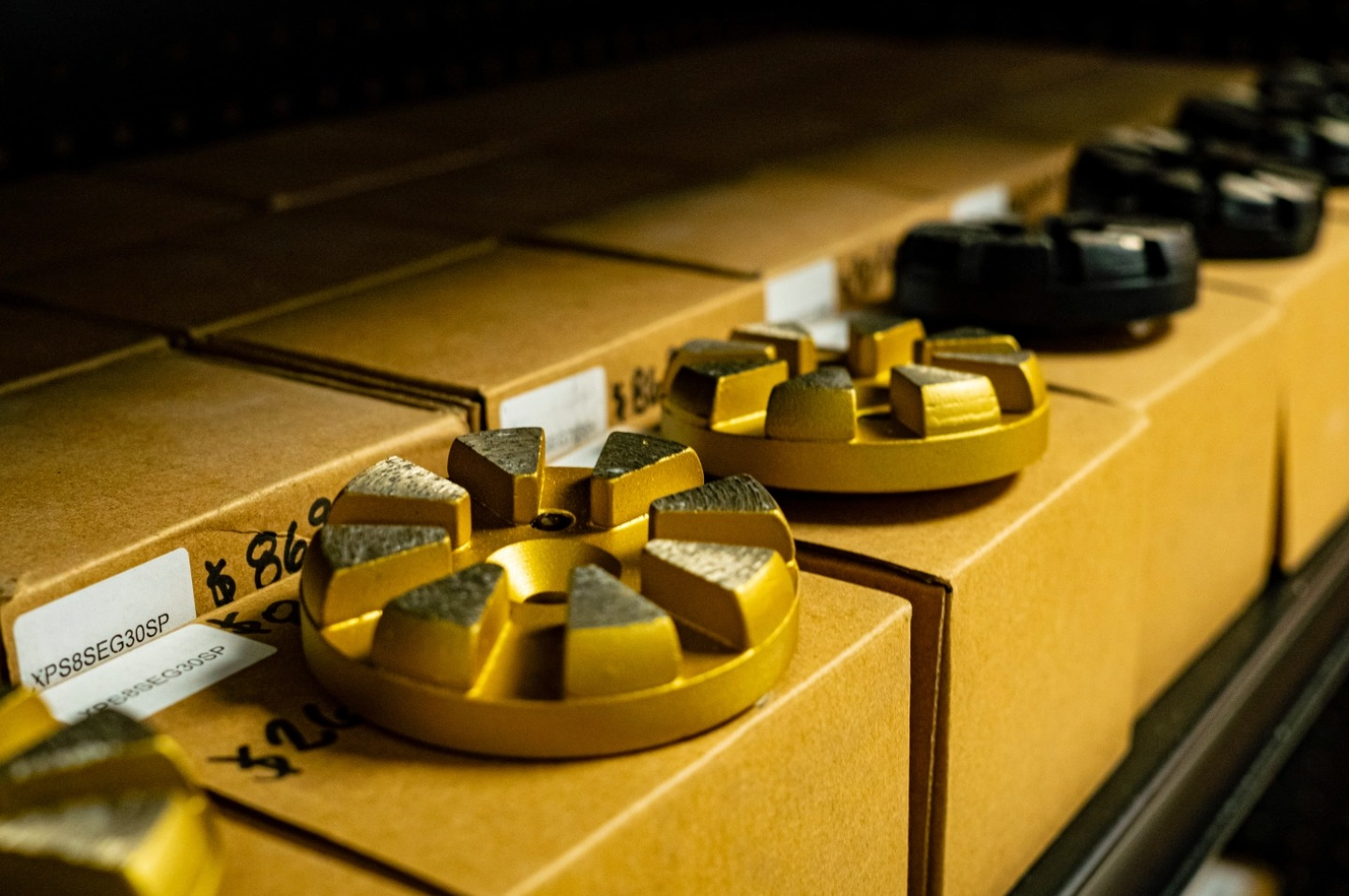 Close-up of yellow and black industrial fittings aligned on cardboard boxes in a warehouse.