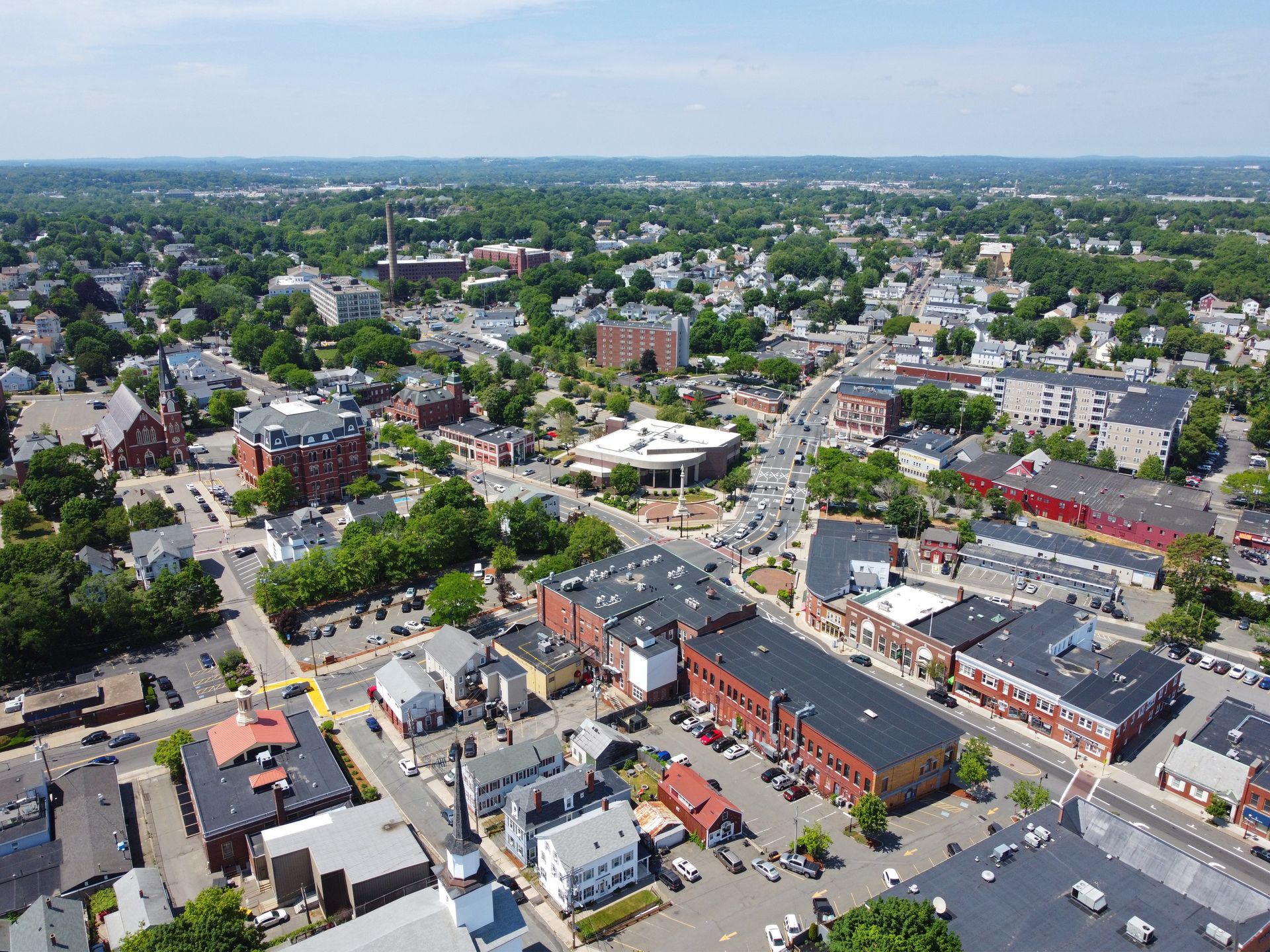 Aerial view of a suburban town center with streets, houses, and a large white canopy plaza