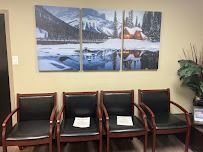 Four black chairs beneath a triptych landscape art piece in a waiting room.