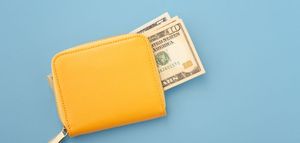Yellow wallet with cash partially visible on a blue background.