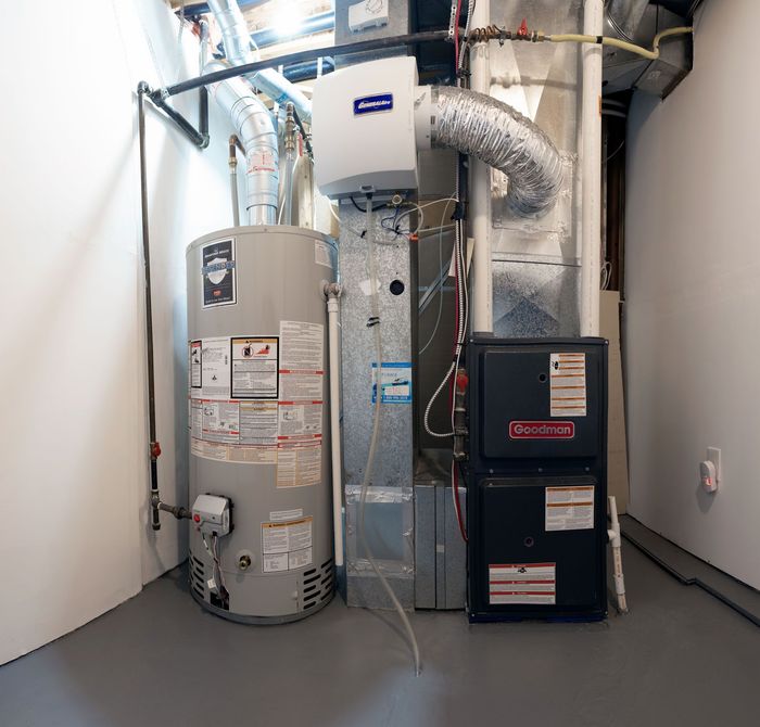 Water heater, furnace, and humidifier in a utility room with gray and white walls.