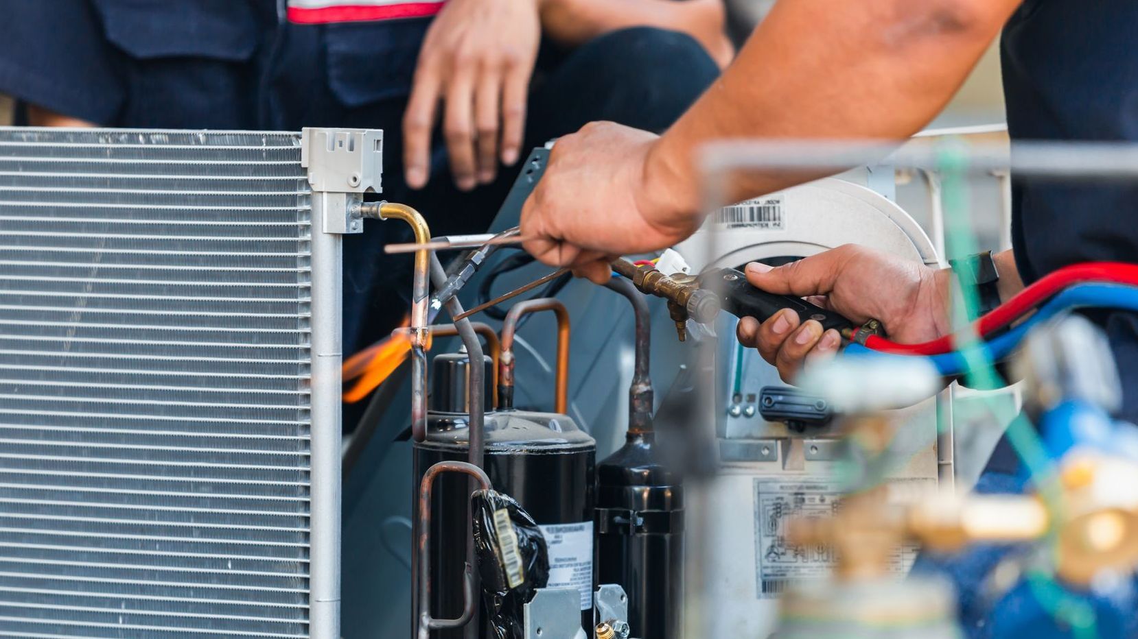 Technician uses a torch to braze copper tubing during an HVAC system repair.