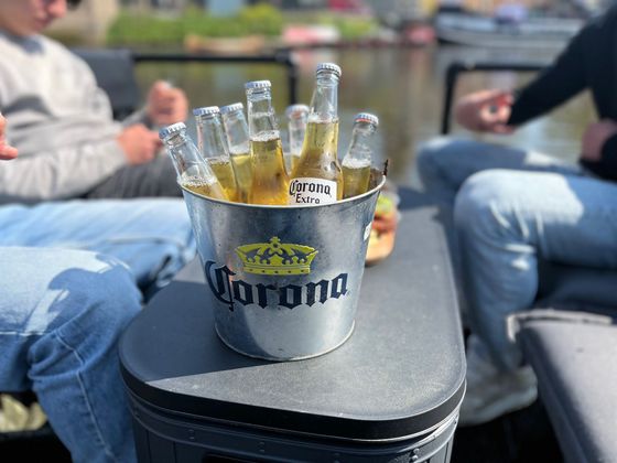 Een emmer Corona-bier op een boot, met twee mensen op de achtergrond.