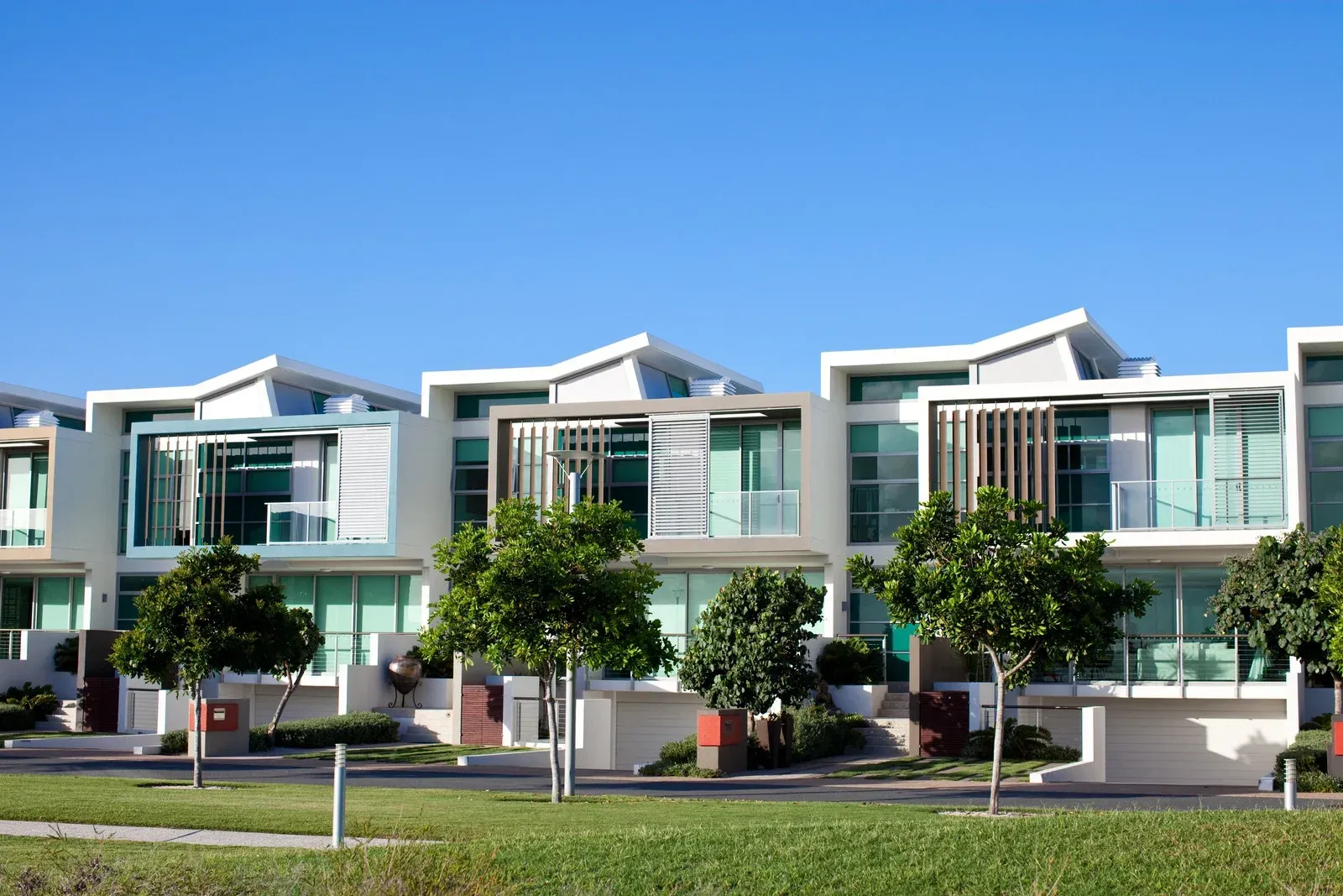 A row of modern houses with trees in front of them