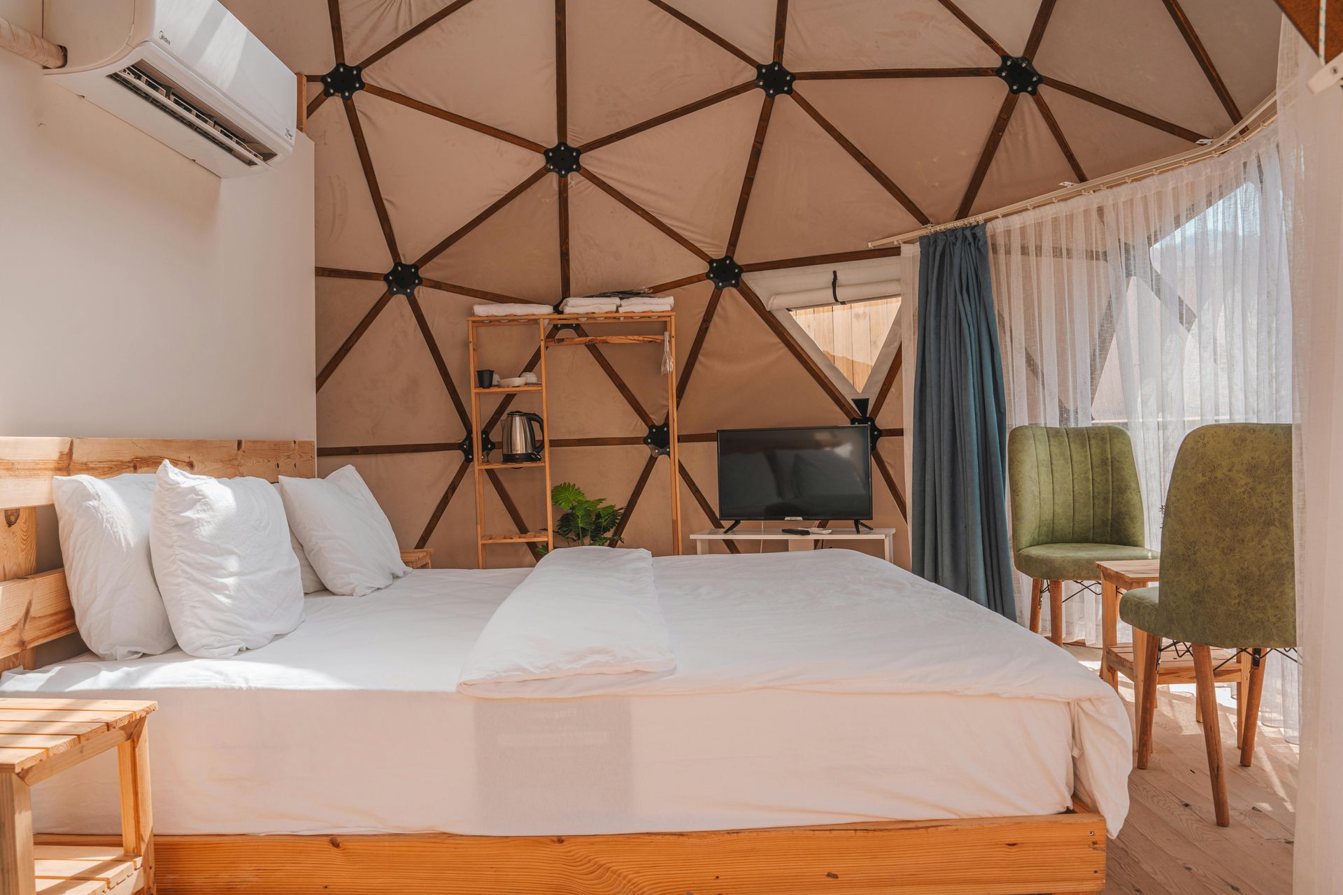 Bedroom with white bed, geometric ceiling, and green chairs.