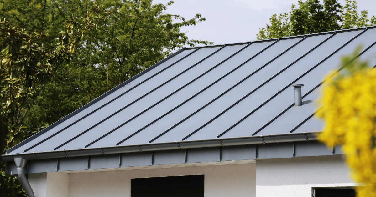 A close up of a roof of a house with trees in the background.