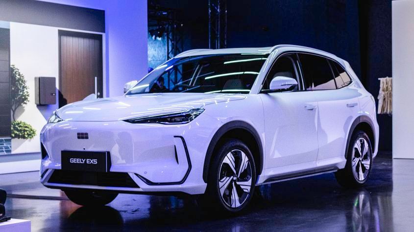 Photo of a white Geely EX5 SUV is a showroom with a black shiny floor