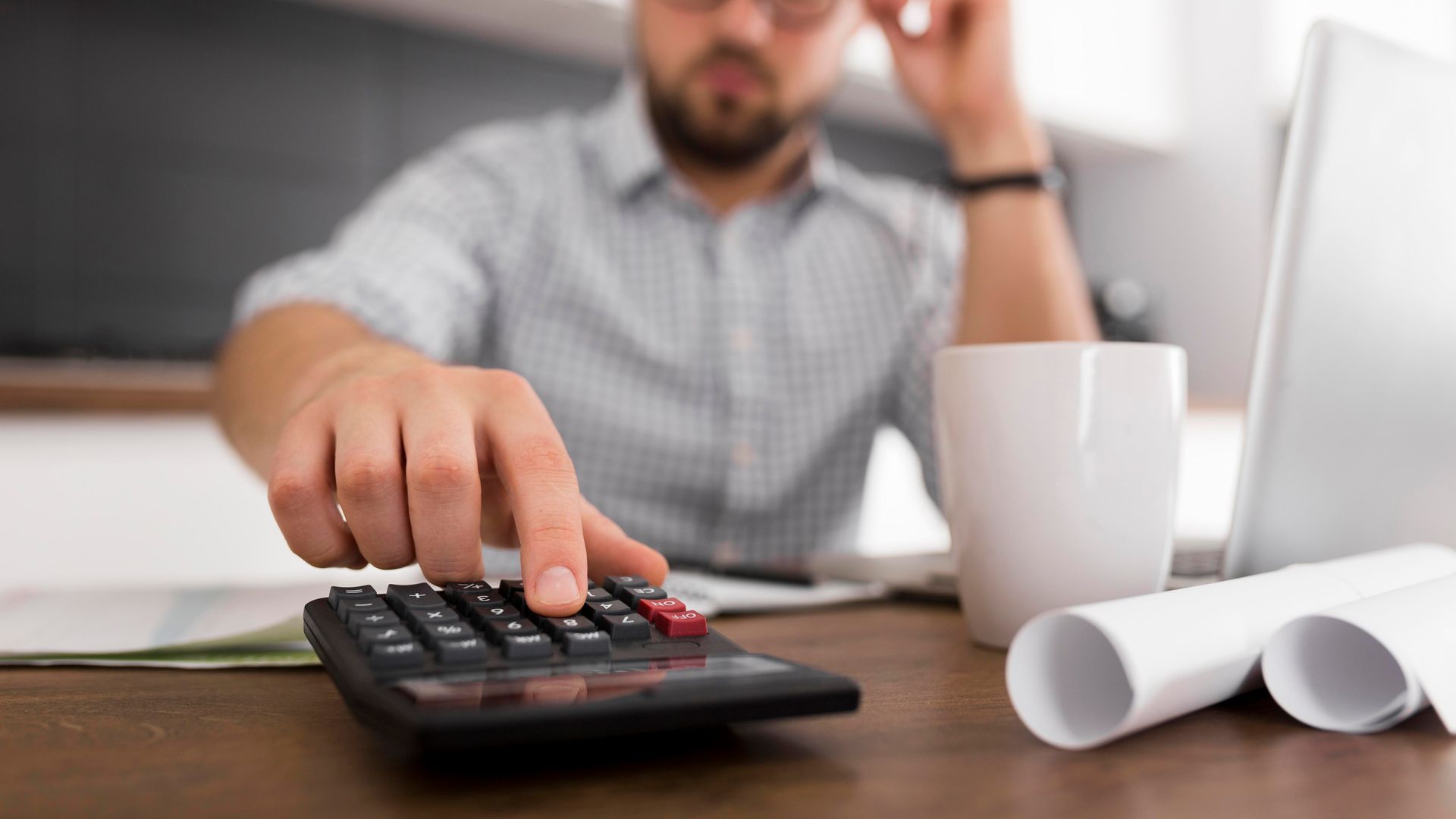 A man is using a calculator at a desk.