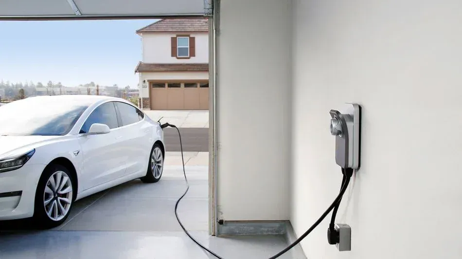 a white tesla model 3 is being charged in a garage at home.
