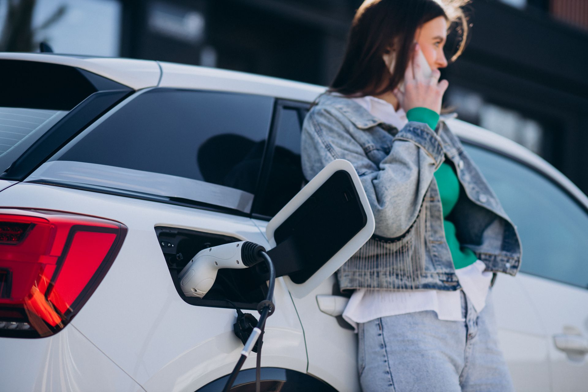 Woman Charging Her Electric Car While She's On The Phone