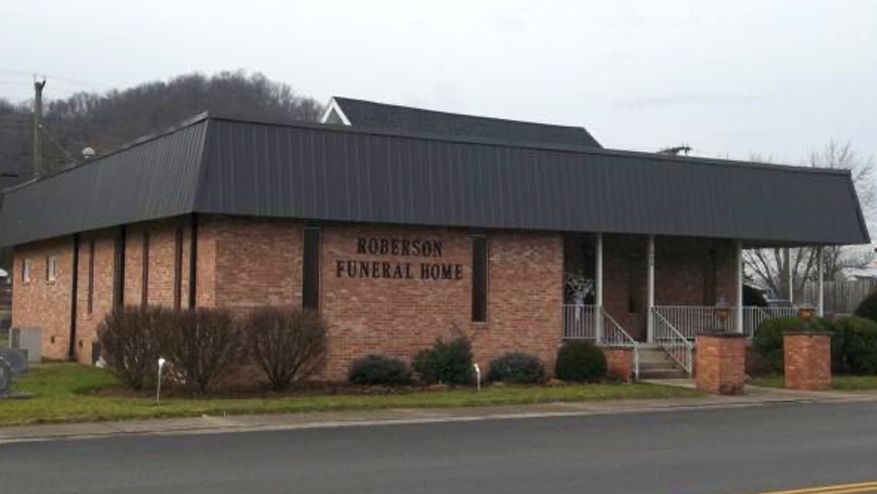 Robinson Funeral Home building, brick exterior, black roof, small bushes, overcast sky.