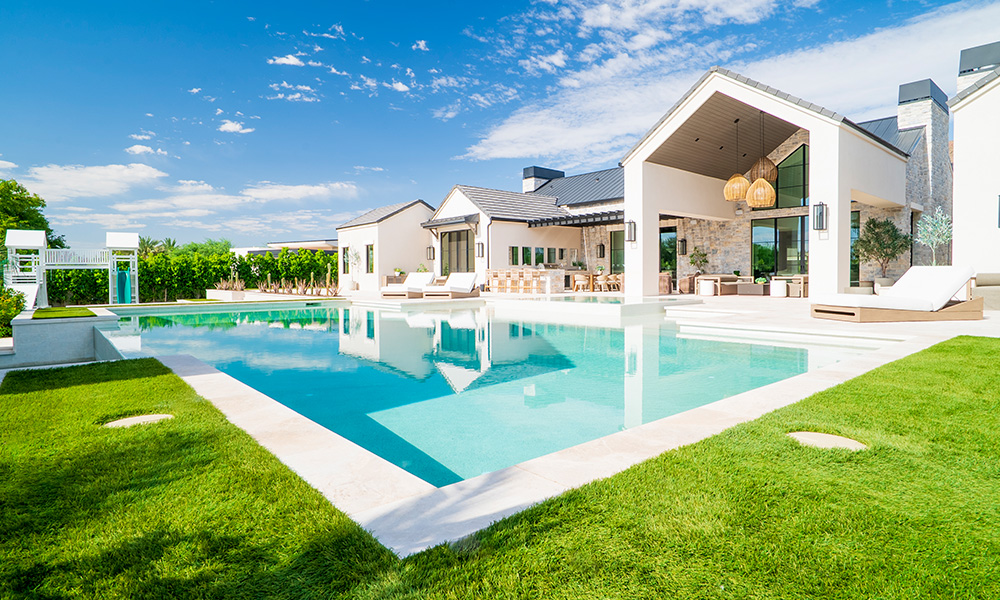 Modern white house with a turquoise pool, green lawn, and bright blue sky Phoenix AZ