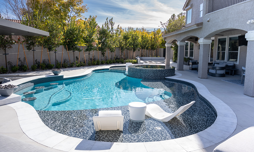 Backyard pool with turquoise water, white lounge chairs, and a covered patio beside a modern house
