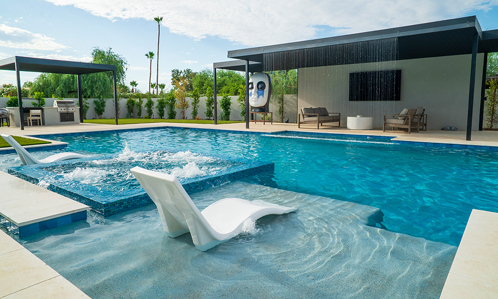 Modern poolside patio with turquoise water, white lounge chairs, and a low building in the background