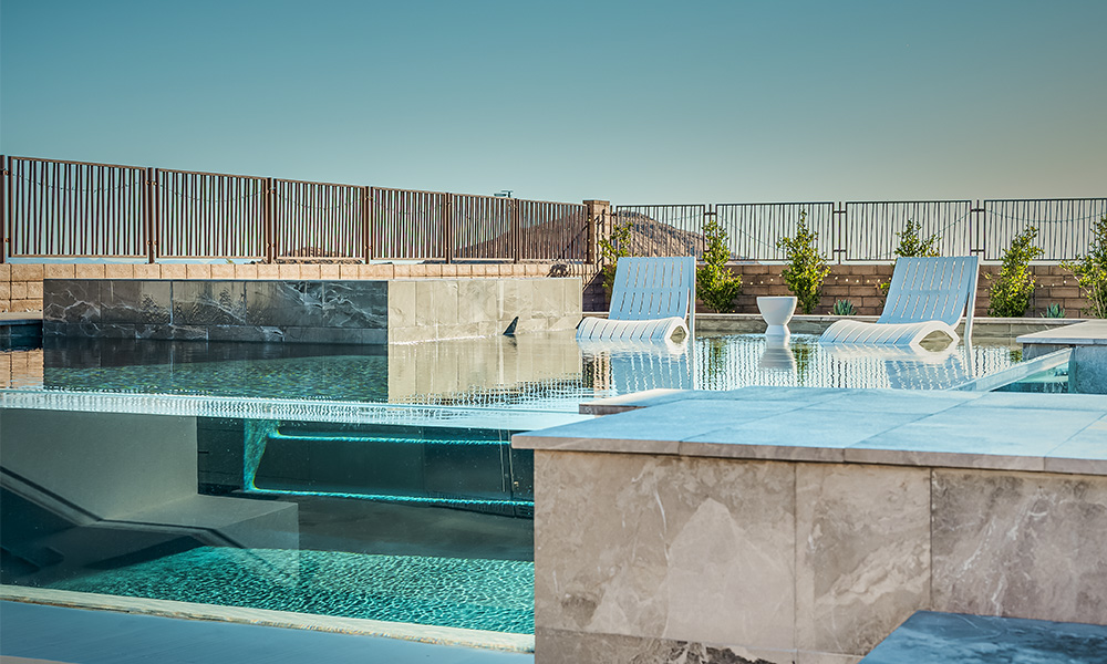 Modern rooftop pool with lounge chairs, blue water, and a clear sky over the city skyline