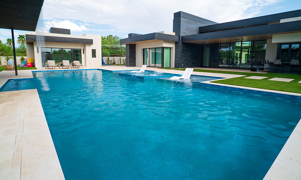 Modern luxury villa with a large turquoise swimming pool and landscaped patio.