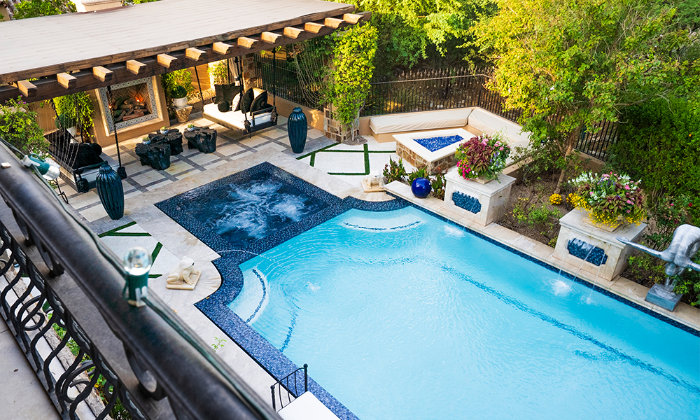 Resort-style pool courtyard with lounge chairs, hot tub, and shaded patio seating