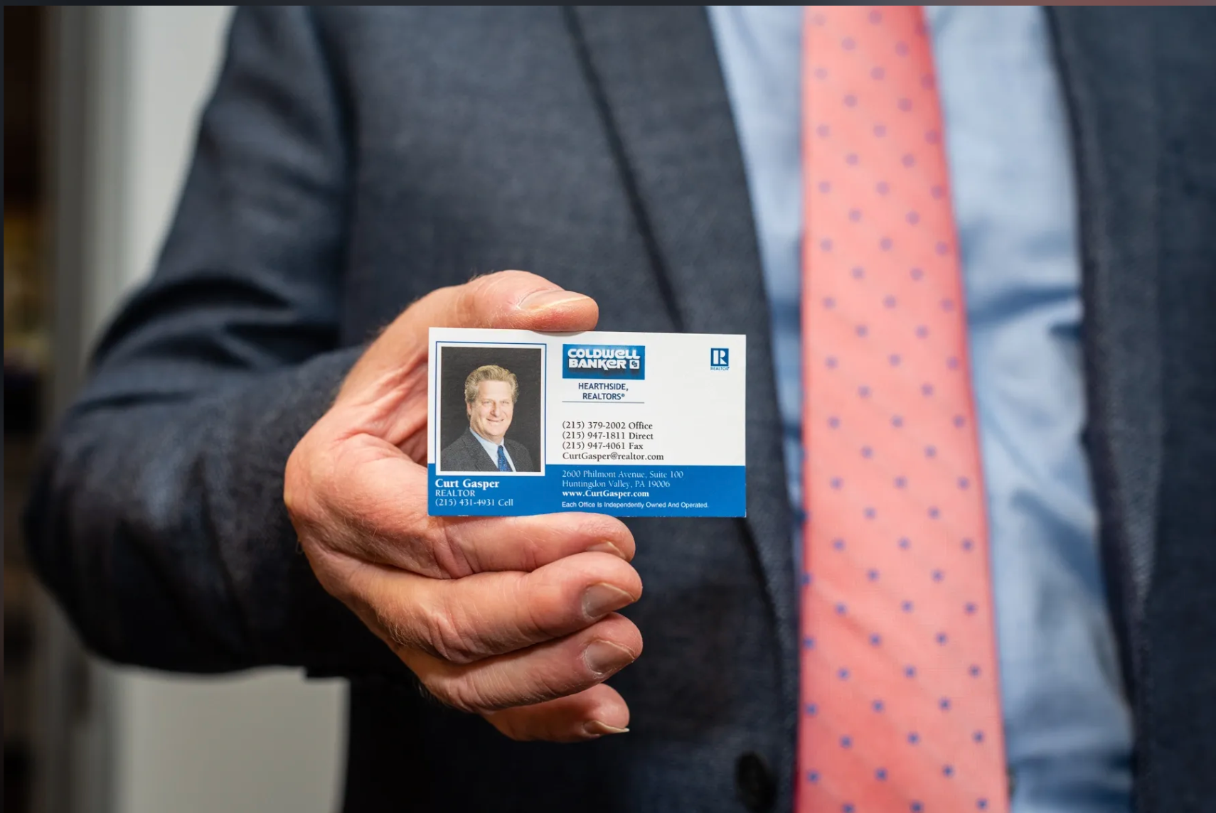 A man in a suit and tie is holding a id card in his hand.