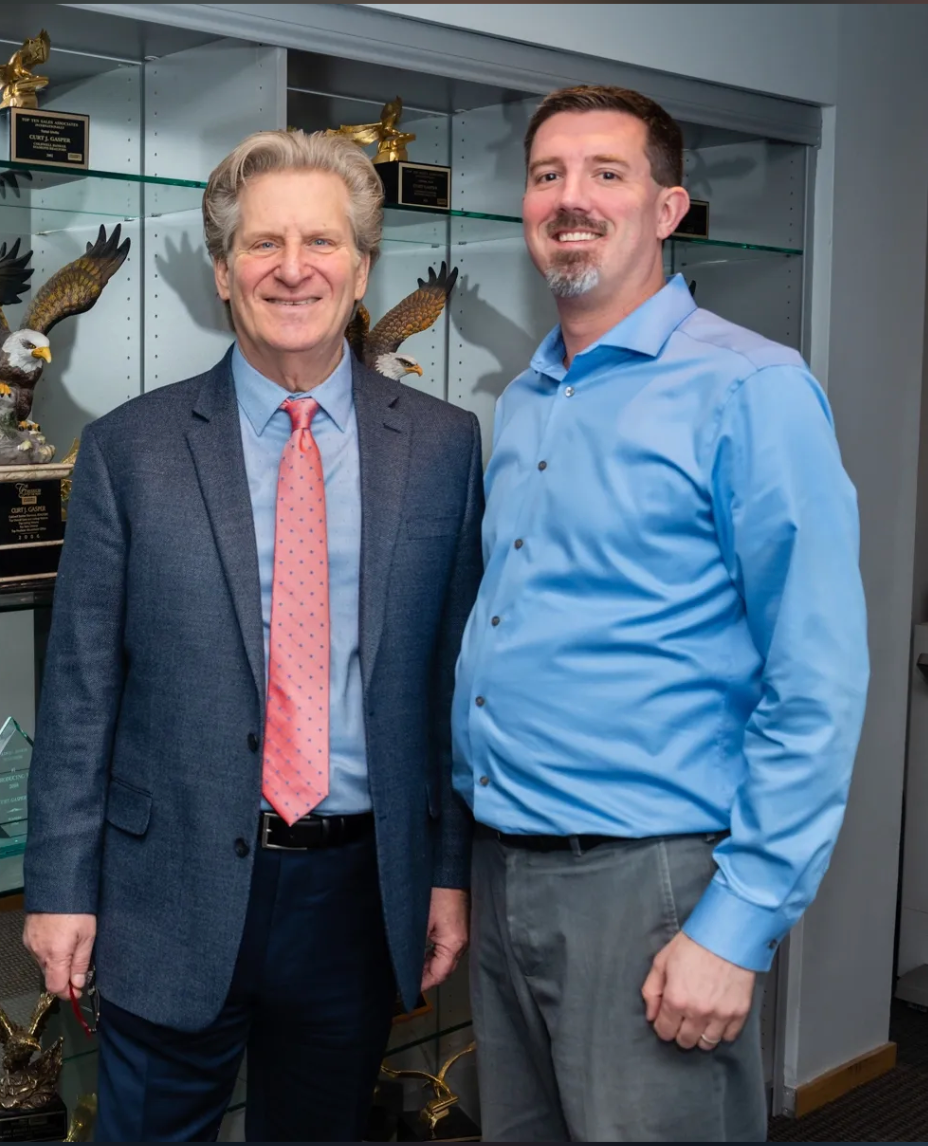 Two men in suits and ties are posing for a picture