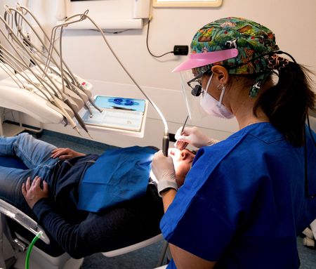 Poltrona odontoiatrica blu e attrezzature in una stanza clinica pulita.
