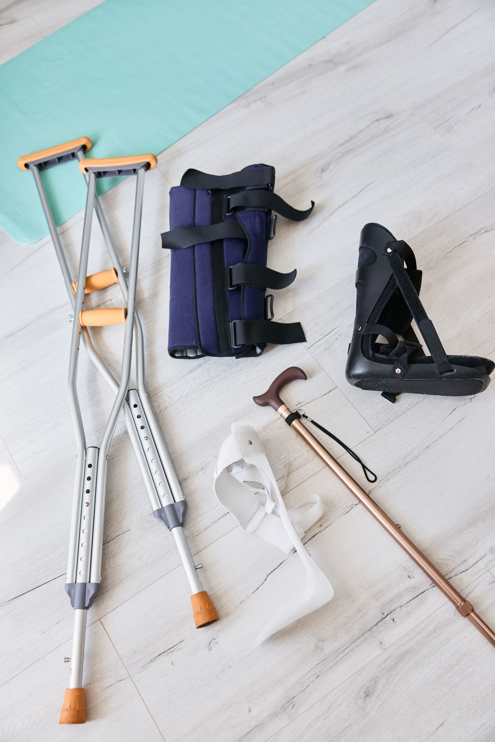 Assorted orthopedic mobility aids and crutches laid out on a light wood floor
