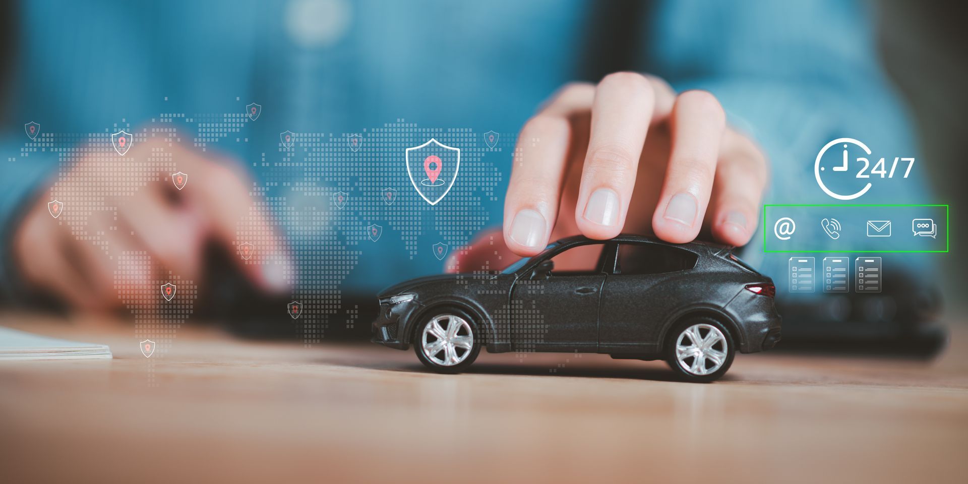 Hand placing a toy car on a laptop, with glowing insurance and 24/7 icons