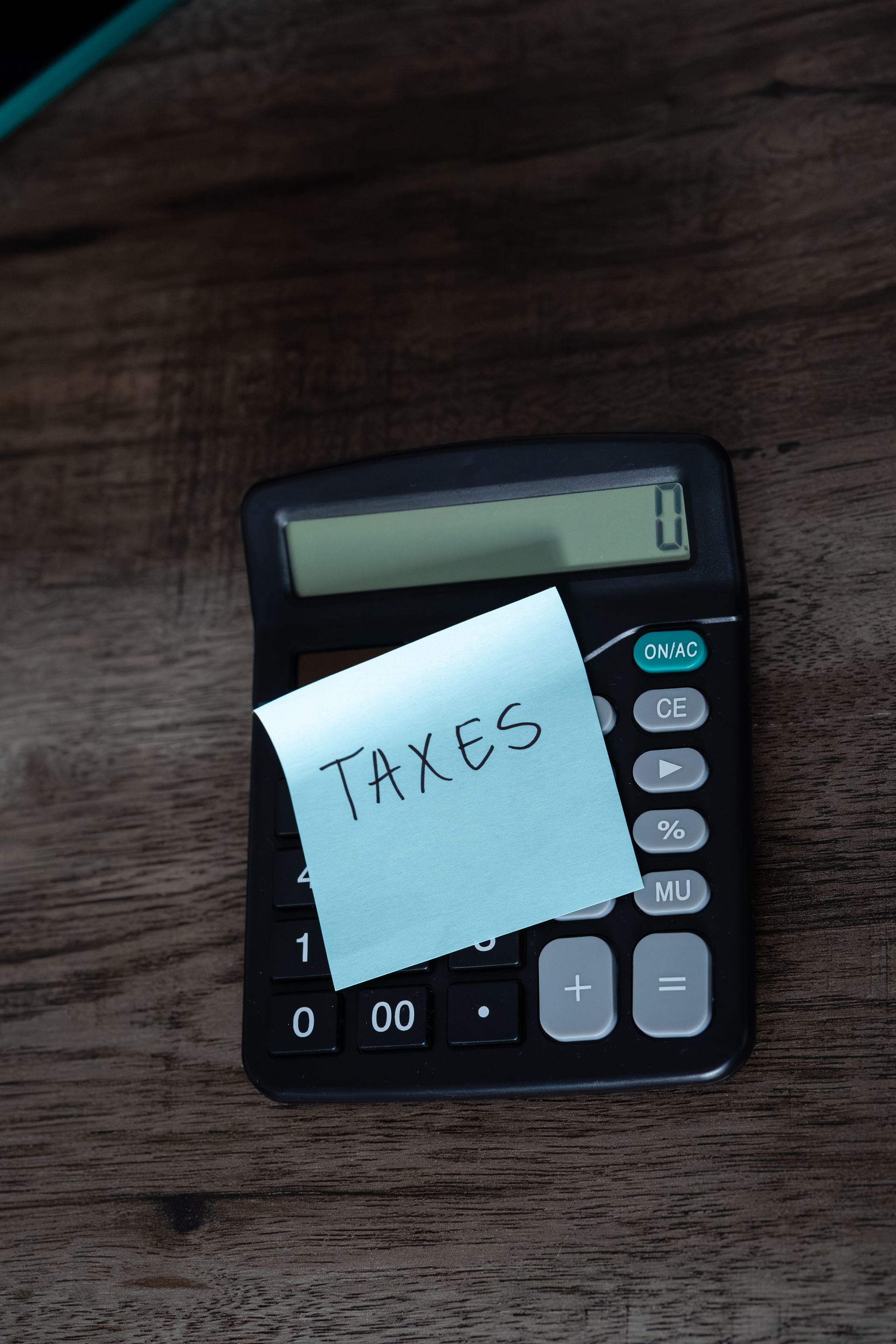 Calculator with a sticky note labeled “TAXES” on a wooden table