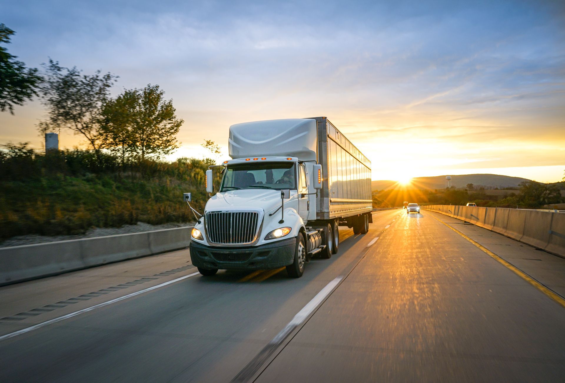 Semi-truck driving on a highway at sunset
