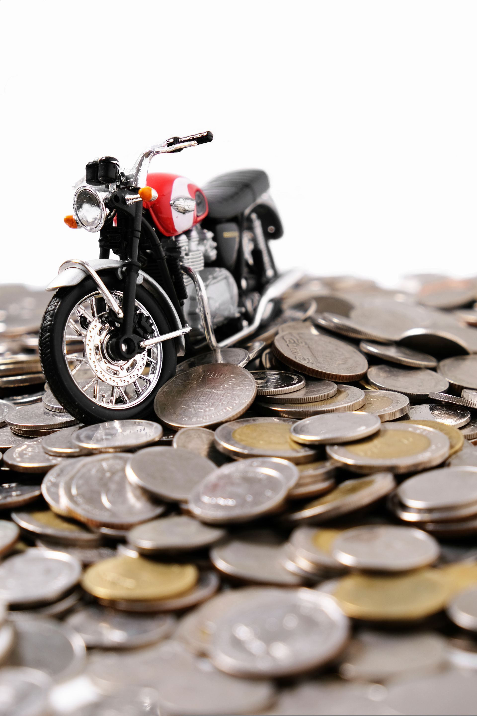 Toy motorcycle on a pile of coins, suggesting saving money or a financial concept