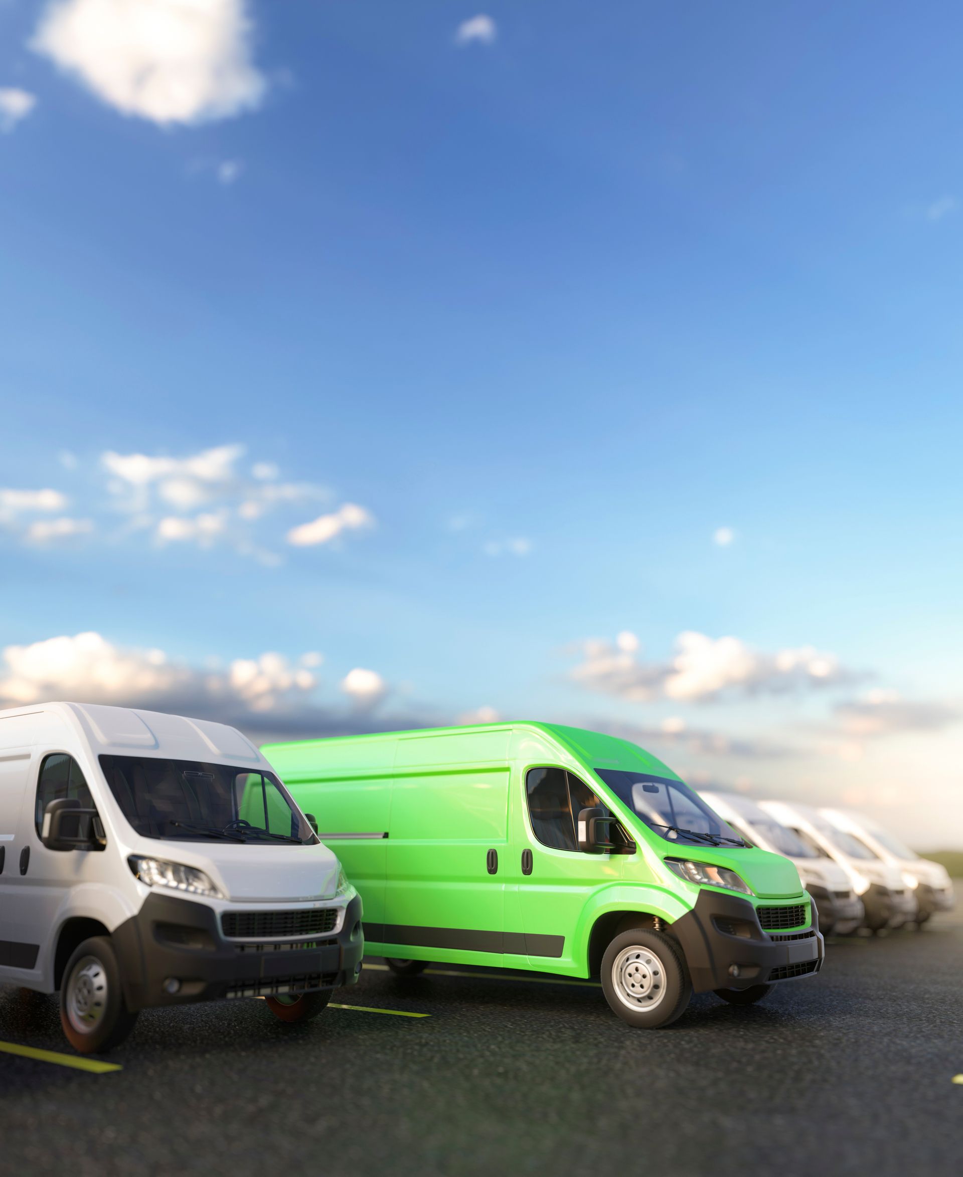 Green and white cargo vans parked in a row under a blue sky