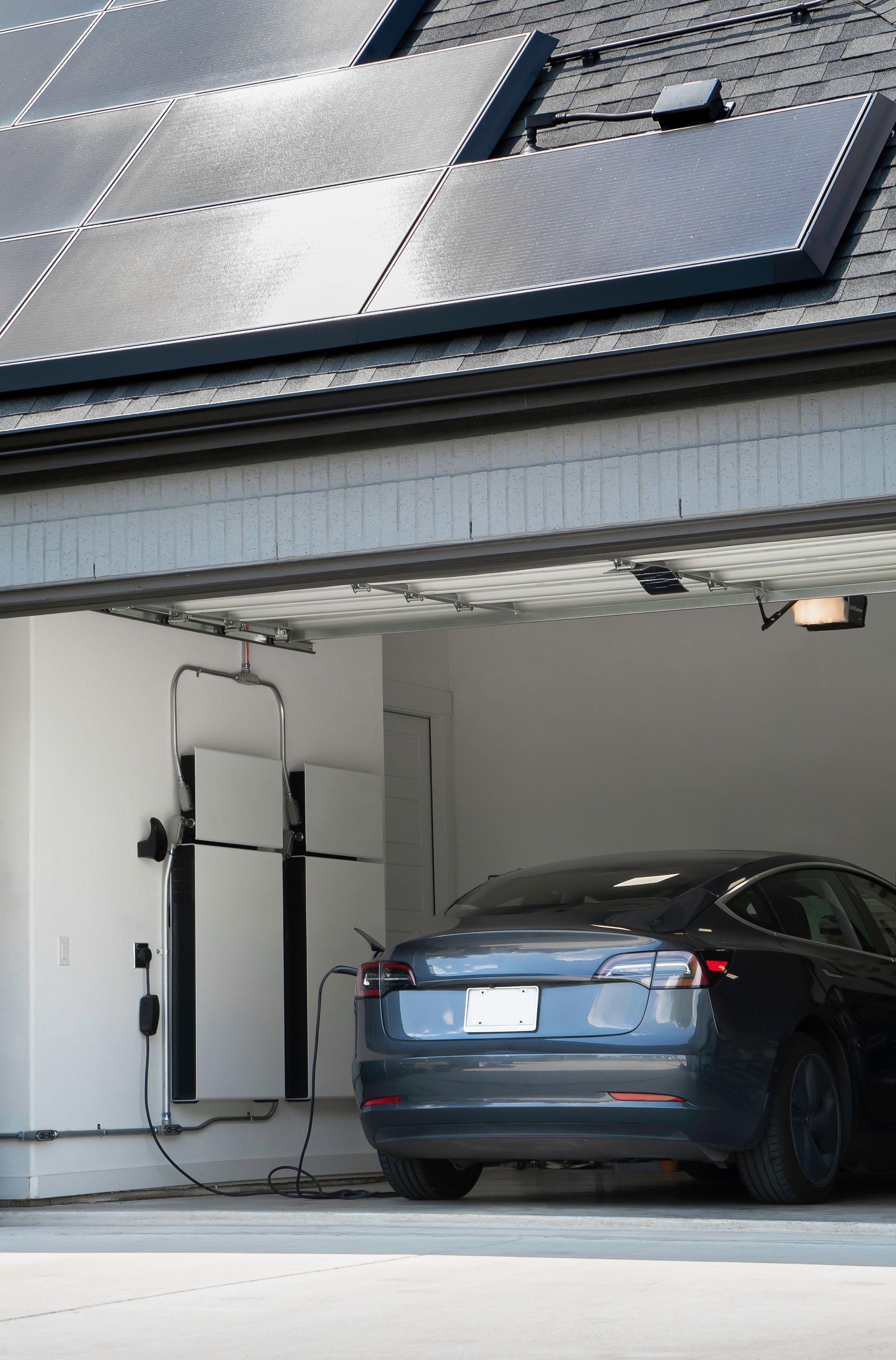Electric car charging in a garage beneath rooftop solar panels