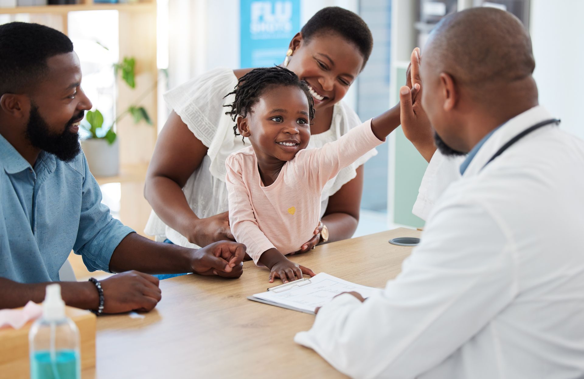 Family meeting with a doctor in a bright clinic, child smiling and reaching toward the clinician